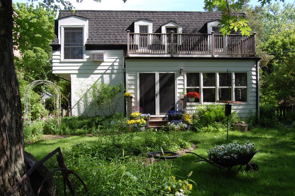 Pansies add spring color to the back of the house. The red flowers are New Guinea impatiens.