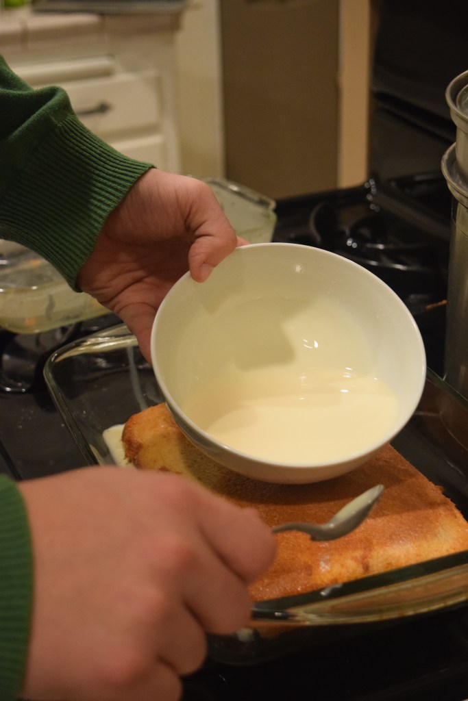 The tres leches being poured onto the cake.